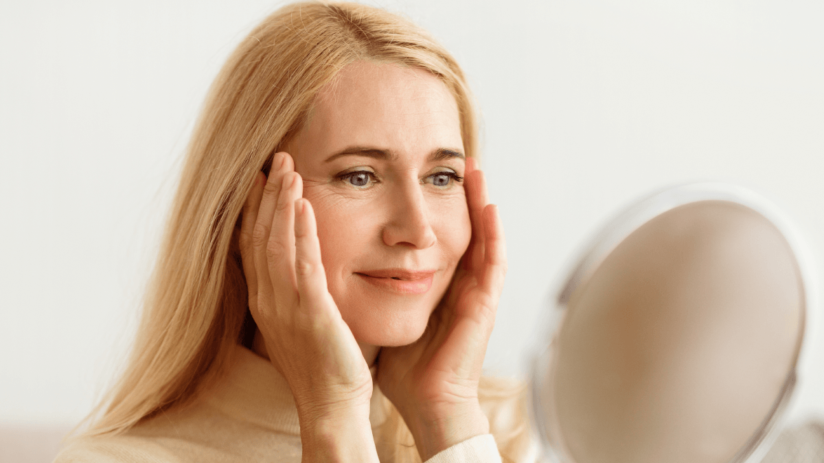 Woman looking at fine lines around her upper lip in a mirror